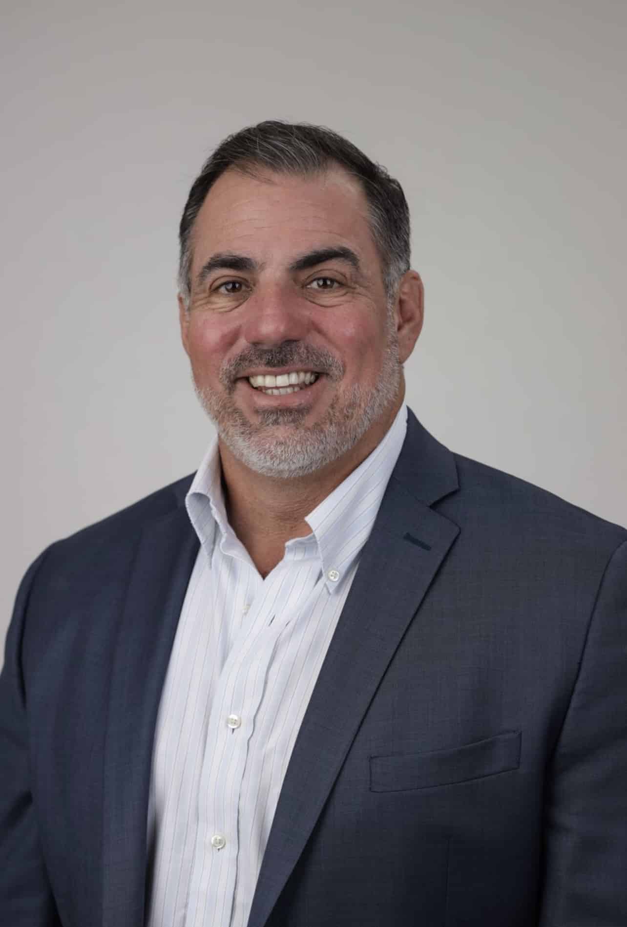 a man wearing a suit and tie smiling at the camera