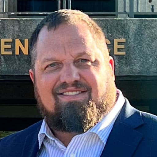 a man wearing a suit and tie smiling at the camera